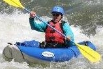 Person in blue kayak paddling through white water rapids